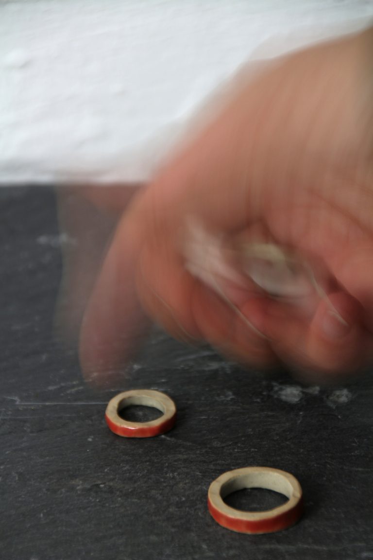 hand grabbing ceramic rings on black stone