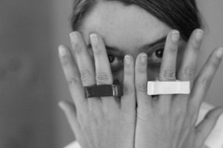 woman covering her face wit the hands, with rings on them