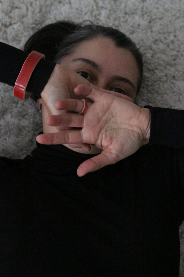 woman laying on a carpet, wearing a ceramic bracelet